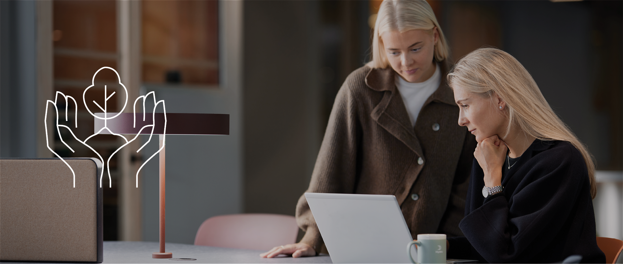 Two persons in an office looking together at a laptop screen 