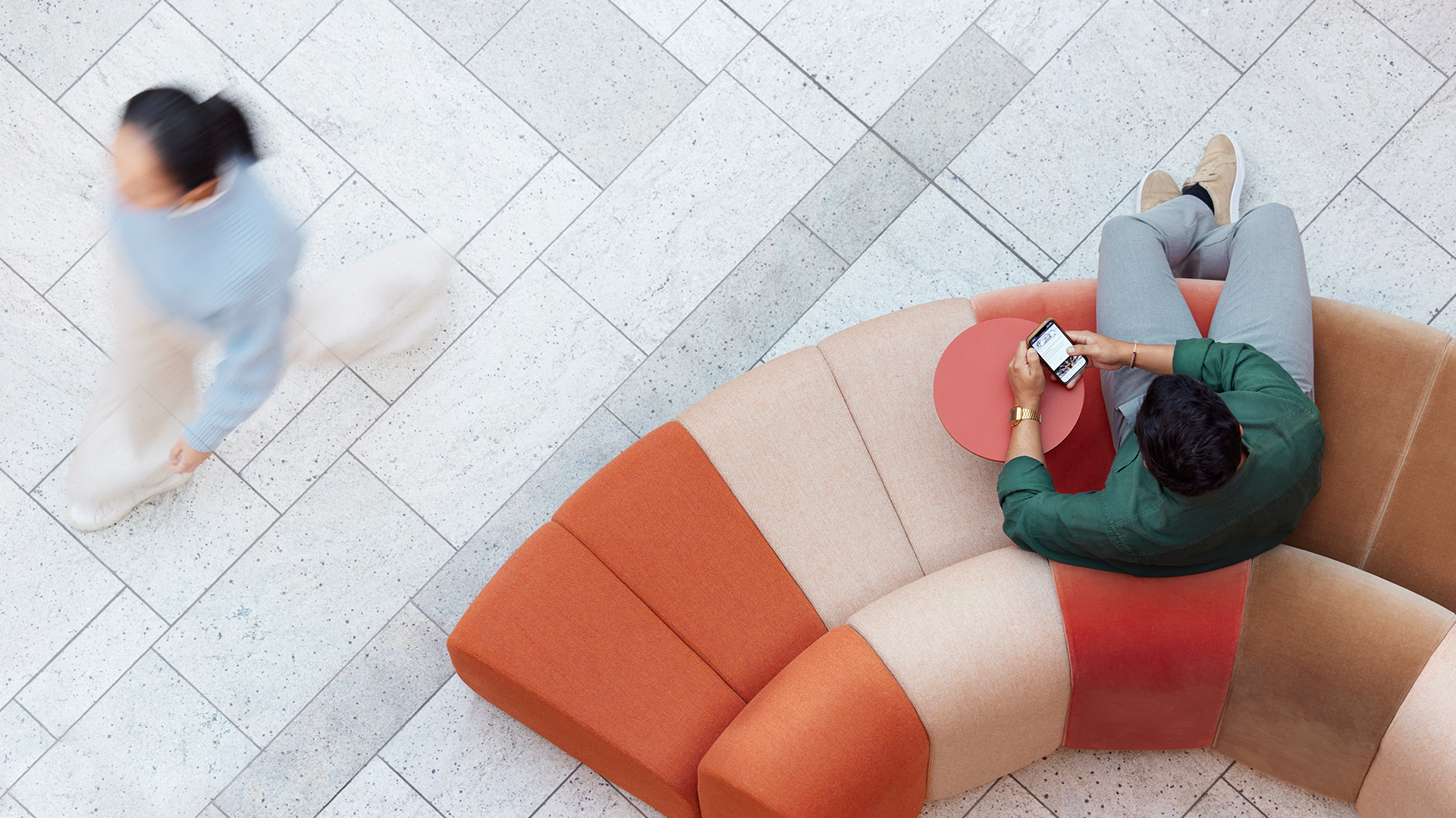 a man and woman sitting on a couch looking at a cell phone