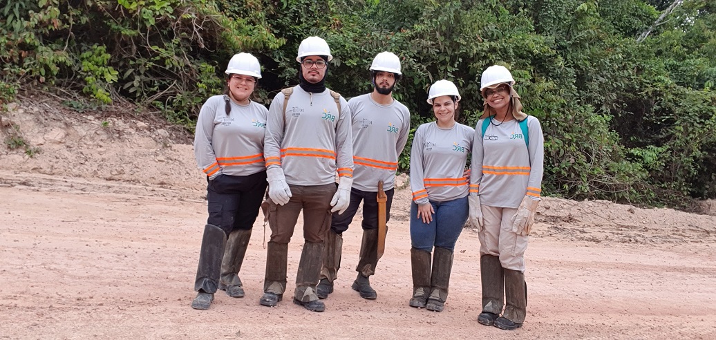 a group of people wearing hardhats and standing on a dirt road