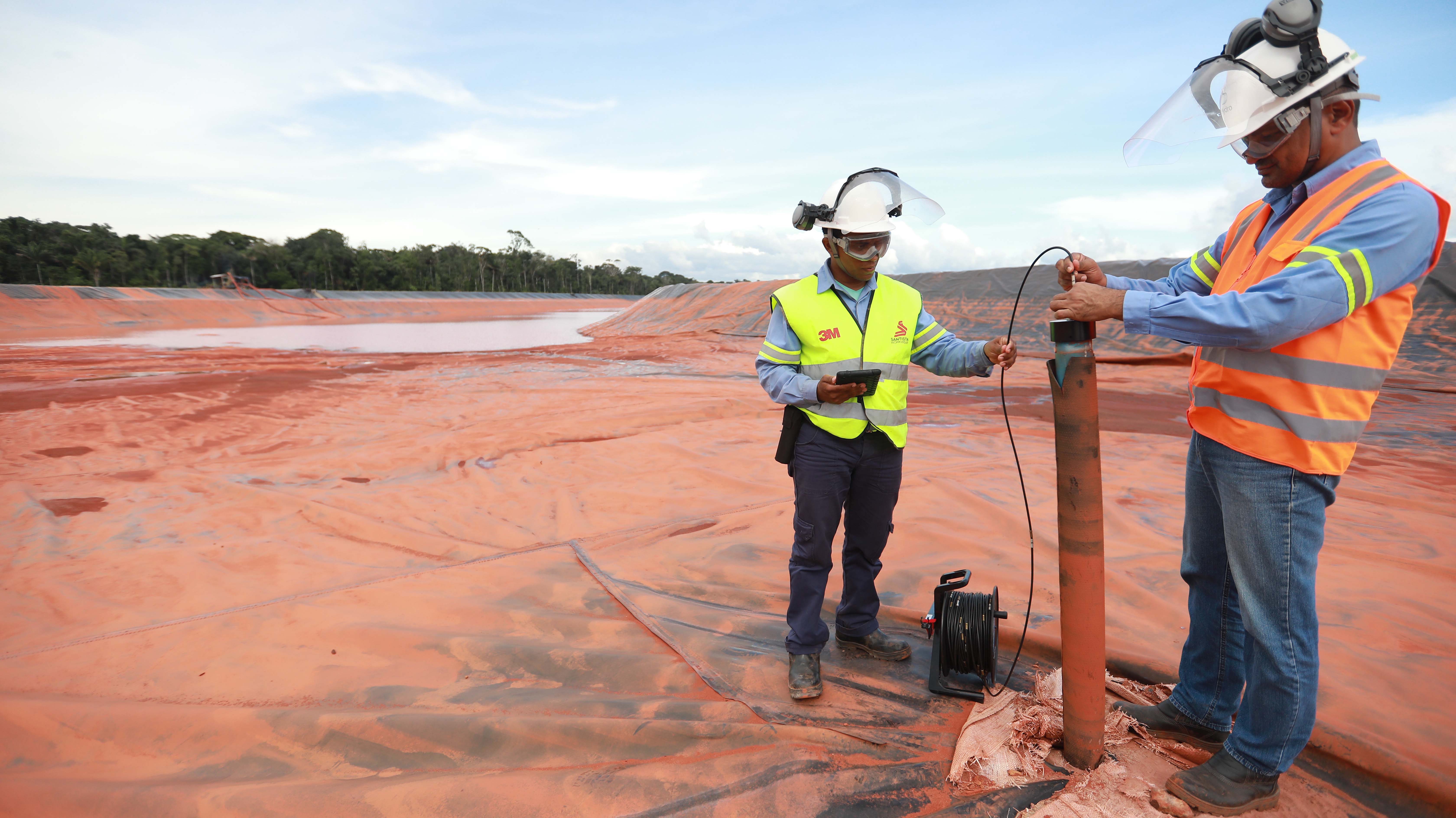 two men wearing hardhats operating an instrument
