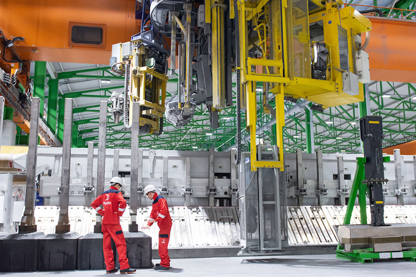 people in red suits standing in front of a large machine