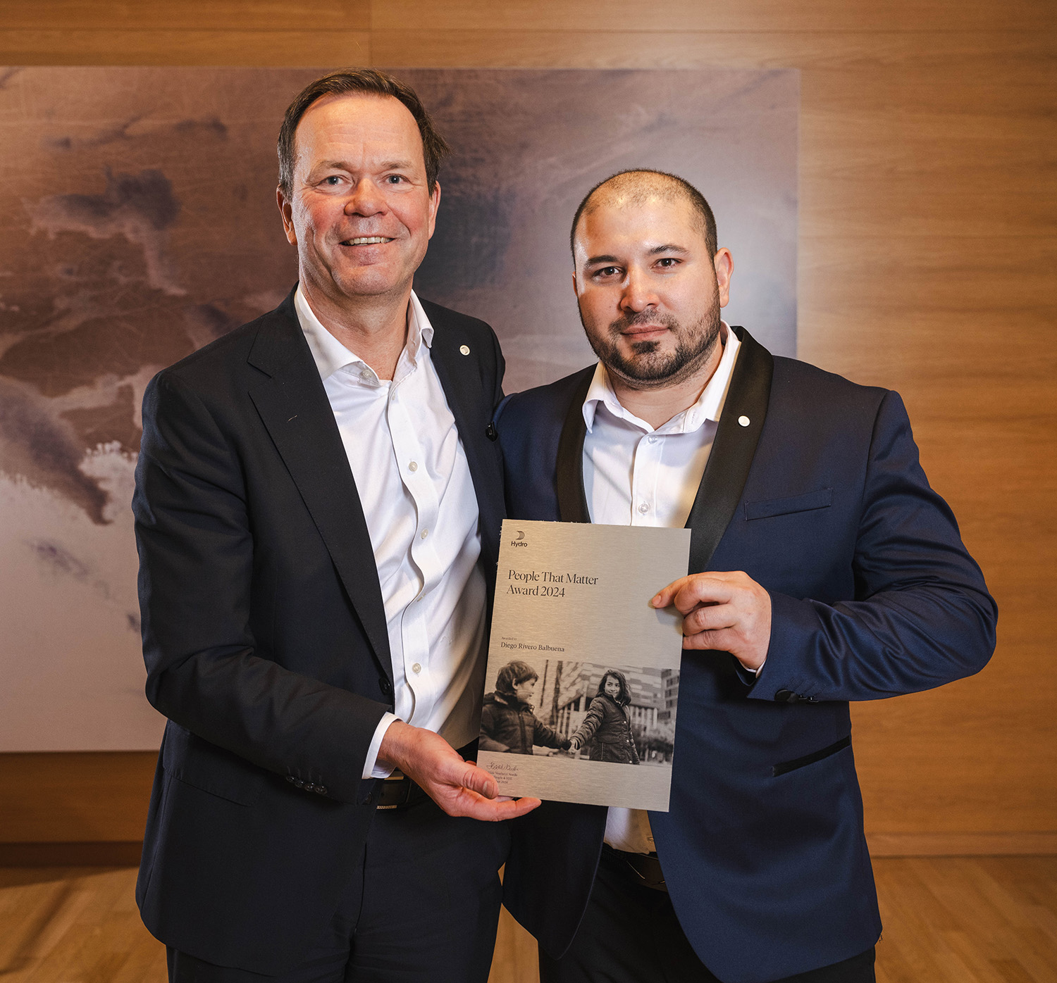 a couple of men holding a framed picture