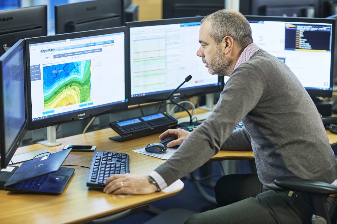 Operator in control room with several computer displays
