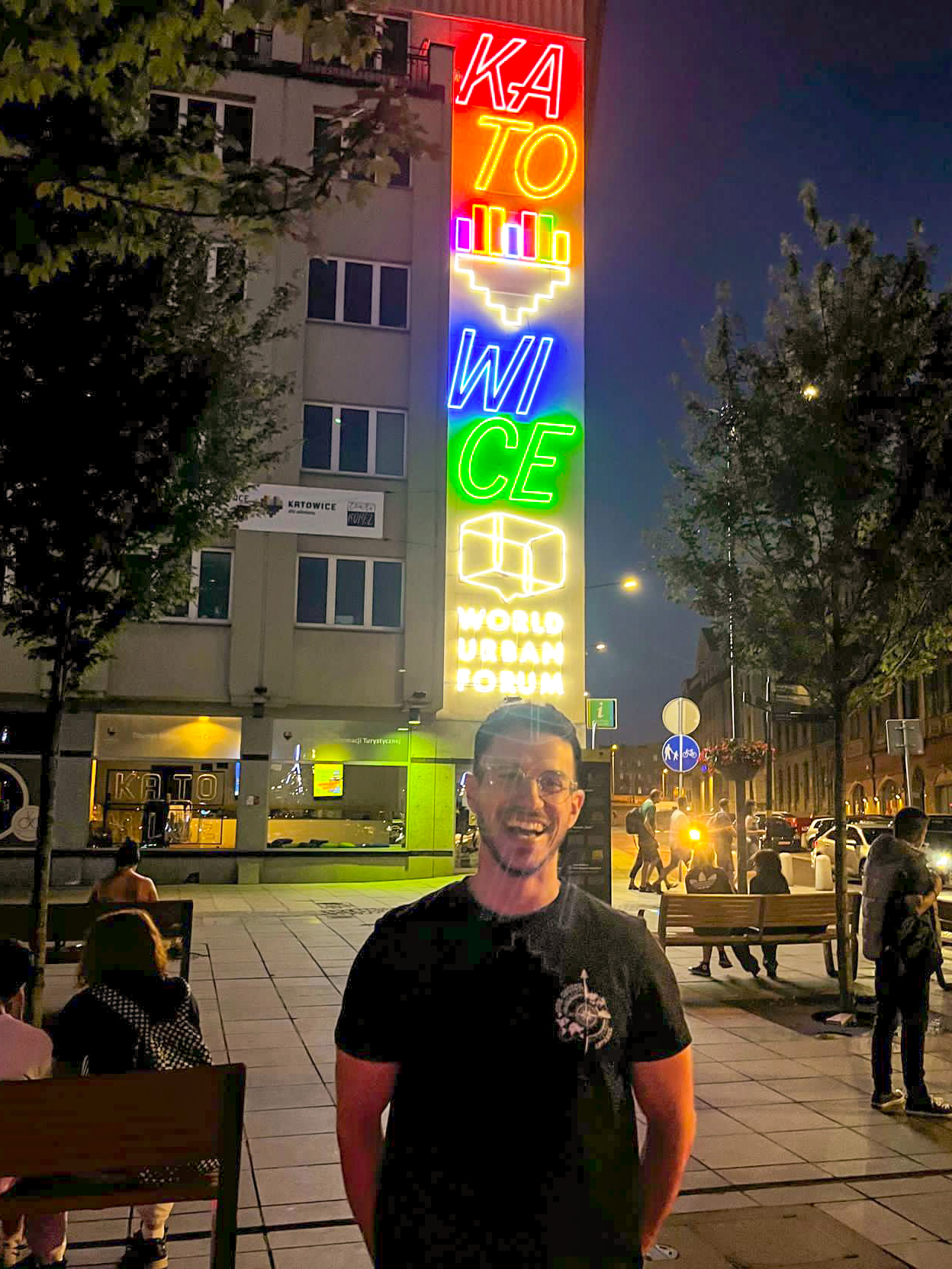 a person standing in front of a building with neon signs